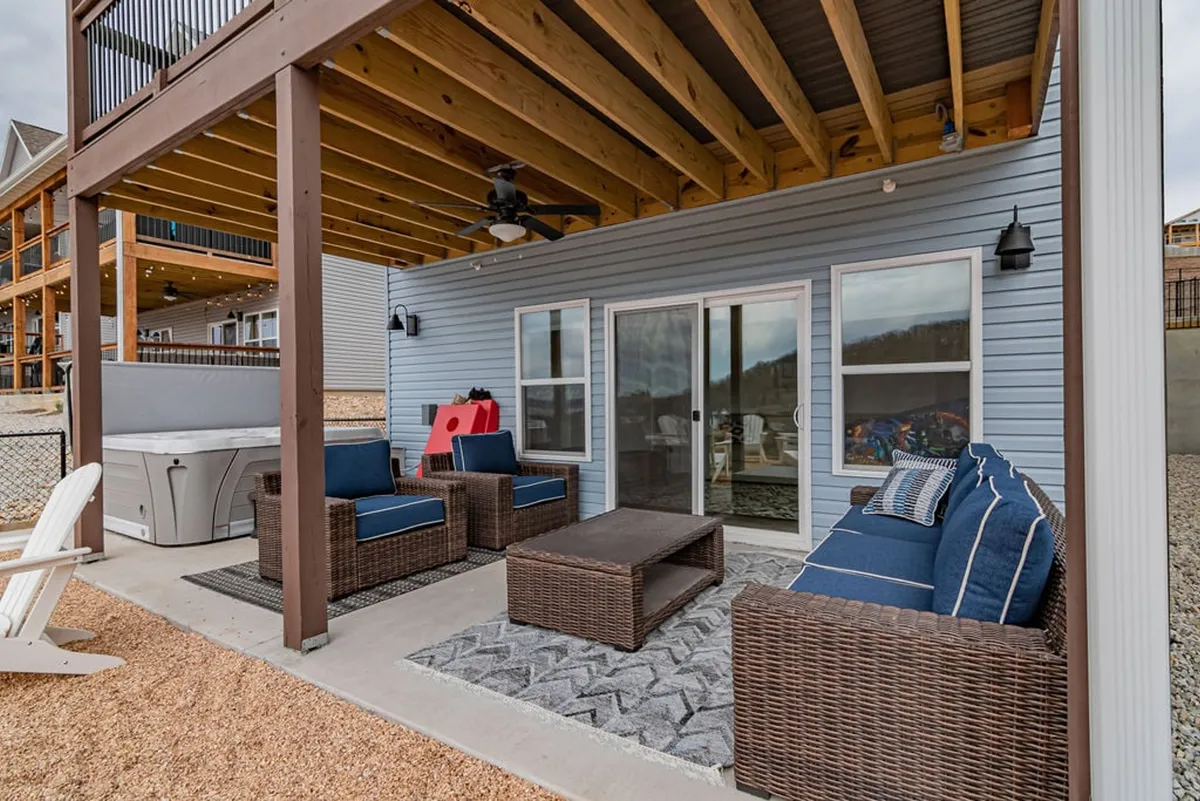 An inviting outdoor seating area with a wooden ceiling, textured rug, and a view through large glass doors to the natural surroundings. The space suggests comfort and connection to the outdoors—ideal for quiet mornings, cozy evenings, and lakeside strolls with your pet.