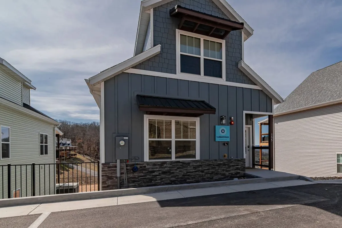A wide exterior view of the house facade with a stone base and large windows, set up for outdoor gatherings, family barbecues, or relaxing on the porch. The space feels open and inviting, ideal for hosting friends or connecting with neighbors.