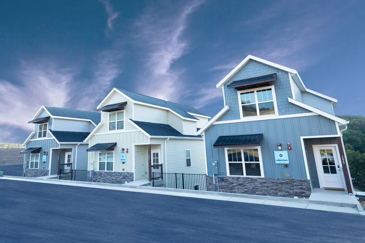 A vibrant exterior shot showcasing the modern architecture of LakeCraze’s community, featuring colorful rooflines and inviting shared spaces. People are seen gathering outdoors, socializing, and relaxing along the street, creating a lively, welcoming atmosphere ideal for group gatherings.