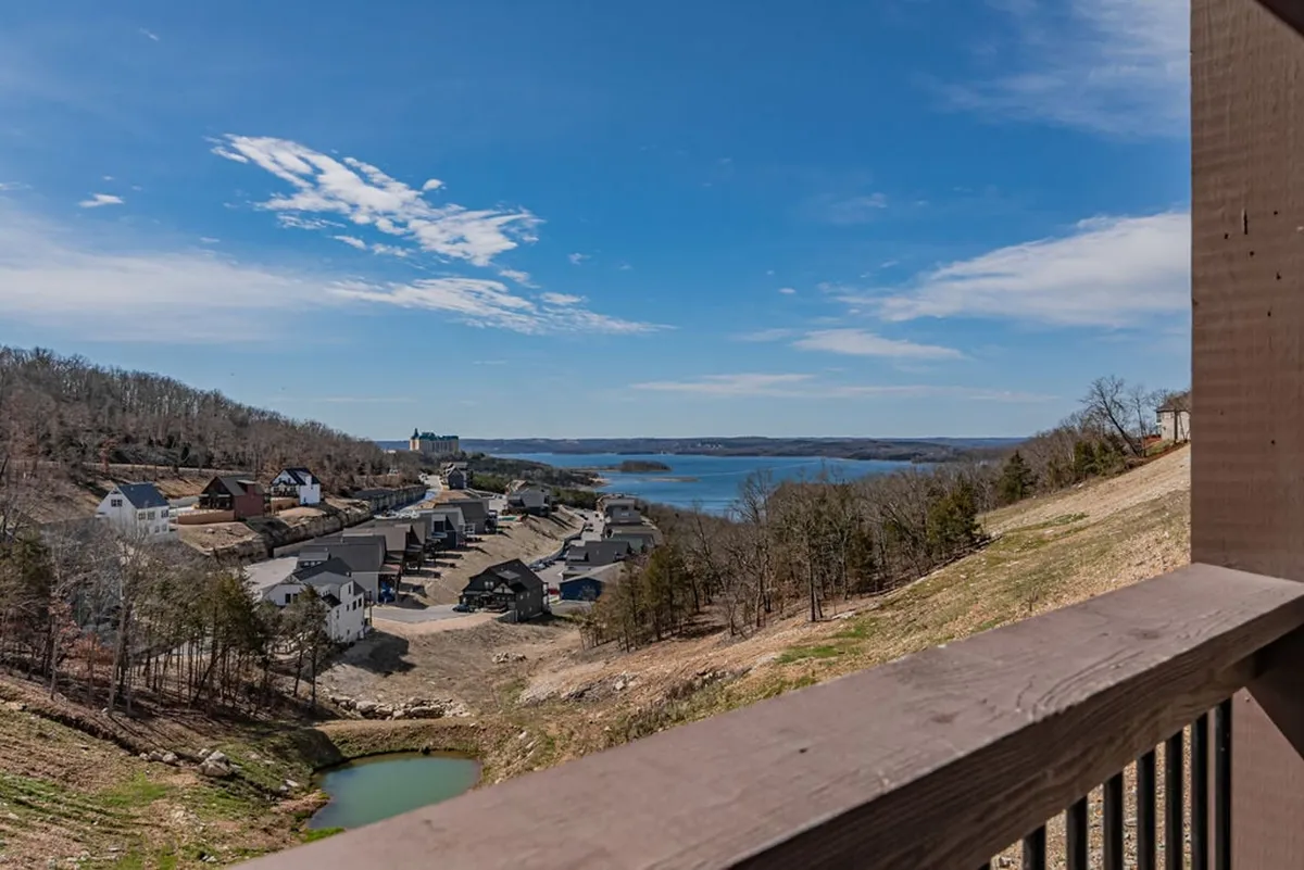 A serene panoramic view of the lake, nearby houses, hills, and open sky. The scene is tranquil, capturing the natural beauty of the area and suggesting endless opportunities for lakeside walks and outdoor fun with pets.