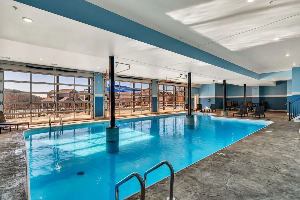 This interior shot features a swimming pool surrounded by large windows and lounge chairs. The tranquil setting is ideal for swimming, sunbathing, or evening swims, offering guests a relaxing escape regardless of the season.