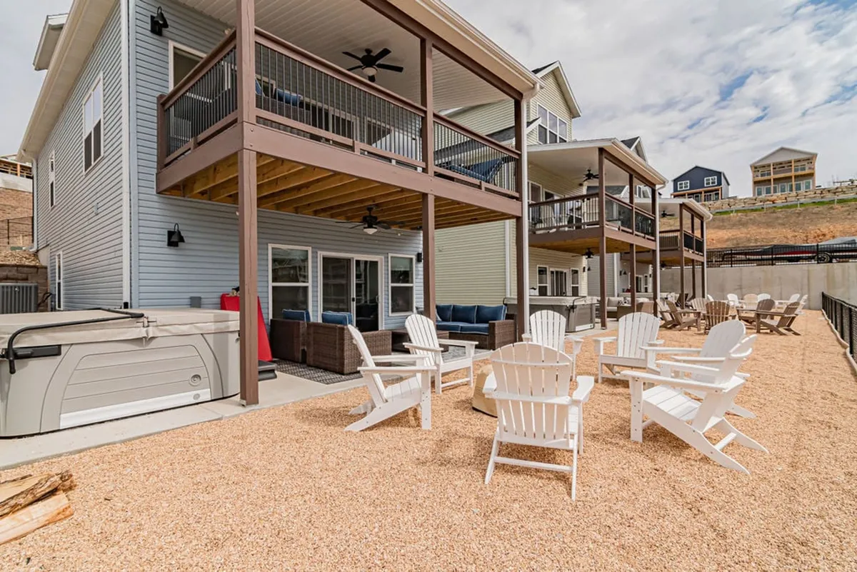 A two-story home with a spacious decked patio featuring Adirondack chairs, perfect for lounging and family gatherings. The deck is set against a backdrop of sunset colors, with ample space for barbecues and casual outdoor meals.